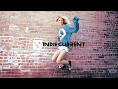 a woman jumping up into the air in front of a brick wall that says, india current