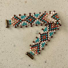 a beaded bracelet is laying on top of a table next to a pair of scissors