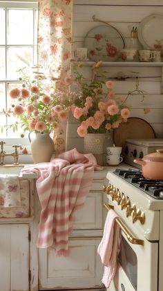 a white stove top oven sitting in a kitchen next to a window filled with pink flowers