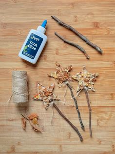 some branches and twigs on a wooden table next to a roll of twine with glue