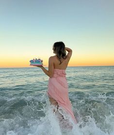 a woman standing in the ocean holding a cake