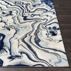 an area rug with blue and white designs on the floor in front of a wooden floor