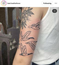 a woman with a tattoo on her arm and some birds flying over the top of her arm