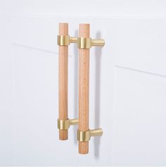 two wooden pegs are attached to the wall with brass hardware on each one side