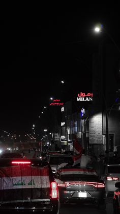 many cars are parked on the side of the road at night in an urban area