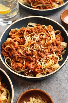 two bowls filled with pasta and meat on top of a table