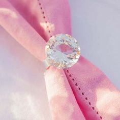 a close up of a pink cloth with a ring on it's end and a white diamond in the center