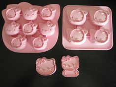 hello kitty cookie molds are shown on a black table with pink plastic trays