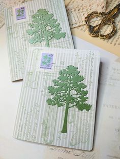 two envelopes with trees on them sitting next to some old papers and scissors,