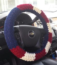 the steering wheel cover is crocheted with red, white and blue yarn