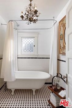 a white bath tub sitting under a chandelier in a bathroom