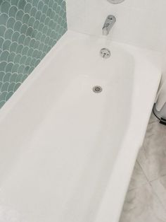 a white bath tub sitting in a bathroom next to a shower head faucet