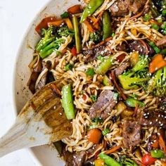 stir fried noodles with beef and vegetables in a white bowl