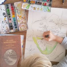 a young boy is drawing with watercolors on paper