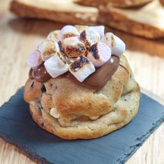 a chocolate chip cookie with marshmallows and other toppings on a slate board