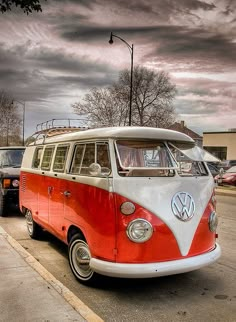 an old vw bus is parked on the side of the road with other cars behind it