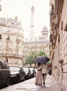 two people walking down the sidewalk with an umbrella