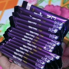 a person holding a stack of purple chocolate bars