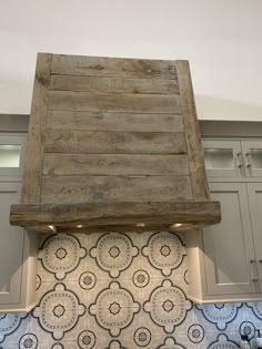 an old wooden stove hood in a kitchen with blue and white tiles on the backsplash