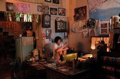 a woman sitting in a room with many pictures on the wall