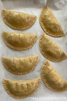 six pastries are lined up on a piece of parchment paper, ready to be baked