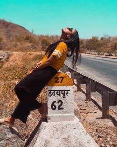 a woman sitting on the side of a road next to a sign that reads 22