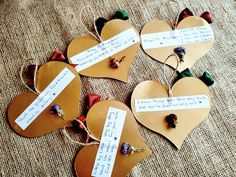 four pieces of heart shaped paper with notes attached to them on a burlap surface