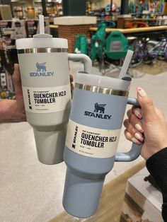 two tumblers are being held up in the air by someone's hand at a store