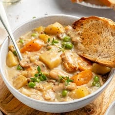 a bowl of chicken and potato soup with a slice of bread