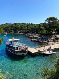 two boats are docked at the dock in clear blue water, with people on it