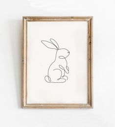 a drawing of a rabbit sitting in front of a white wall with a wooden frame