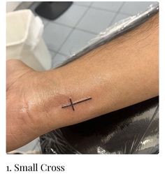 a small cross tattoo on the arm