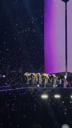 a group of people standing on top of a stage with confetti in the air