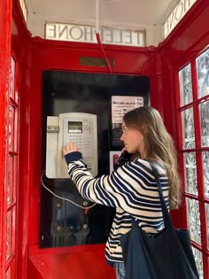 a woman in striped shirt using a phone booth