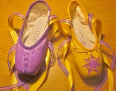 two pairs of purple and yellow ballet shoes on a wooden table with ribbons around them