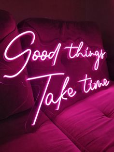 a pink neon sign that says good things take time on the back of a couch