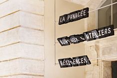 four black street signs hanging from the side of a white building with french writing on them