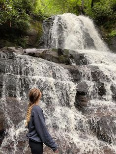 a woman standing in front of a waterfall