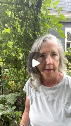 an older woman standing in front of some plants