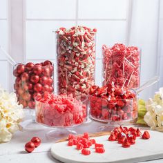 there are many different types of candies on the table with white flowers in the background