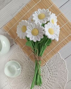 a bouquet of daisies on a doily next to a cup and saucer