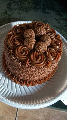 a chocolate cake sitting on top of a white plate covered in swirls and nuts