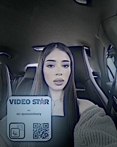 a woman sitting in the back seat of a car holding up a video star sign