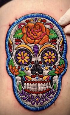 a woman's stomach with a colorful sugar skull tattoo on it