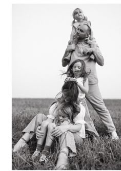 a woman and two children are sitting in the grass with their mother holding her baby