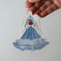 an angel ornament hanging from a string in the shape of a dress with a strawberry on it