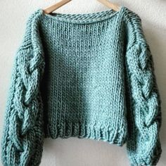 a green sweater hanging on a wooden hanger