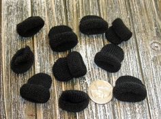 black knitted hats and buttons laying on a wooden surface next to a penny coin