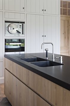 a kitchen with white cabinets and black counter tops in front of an oven that is built into the wall