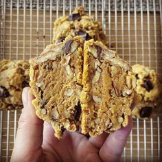 a person holding up some cookies on a cooling rack with chocolate chips and almonds